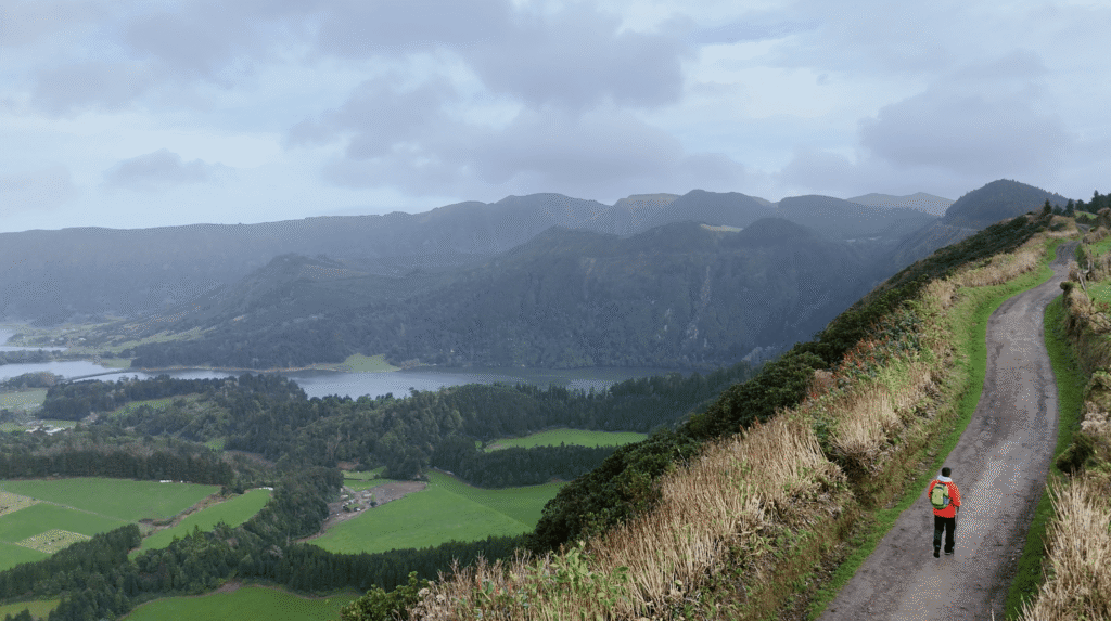 Hiker on ridge trail overlooking Sete Cidades crater lakes on São Miguel Island during a guided Azores hiking tour