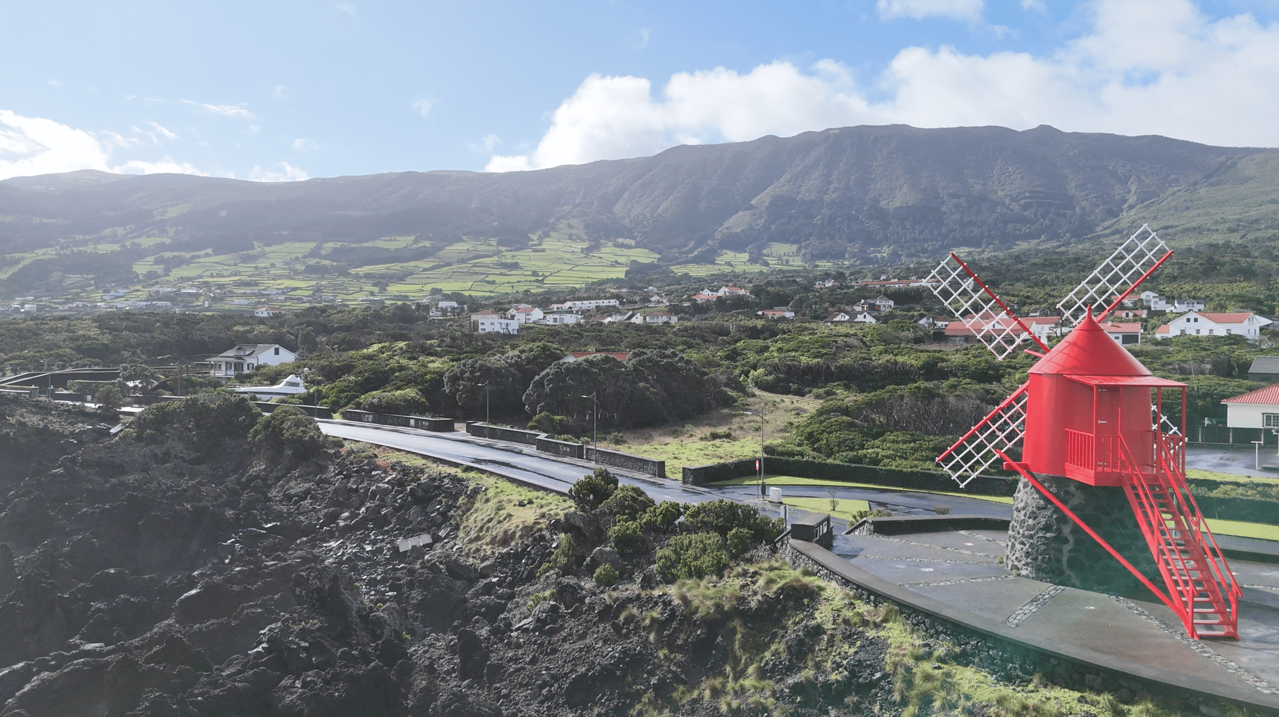 Red windmill overlooking the volcanic coastline on Pico Island in the Azores during a self-guided hiking tour